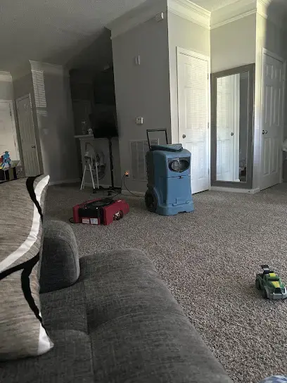 Dehumidifier and air mover drying a carpeted living room in a Gwinnett home