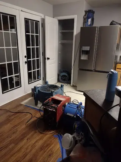 Air movers and a dehumidifier drying a wet hardwood floor
