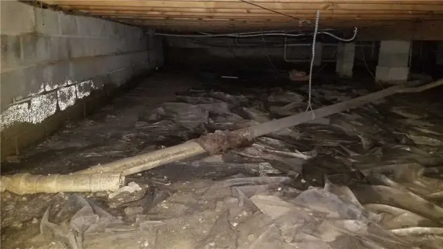 Crawl space under a Gwinnett home with a wet, torn vapor barrier after storm runoff