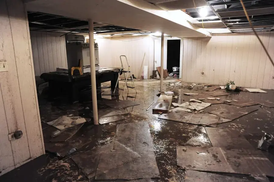 Flooded finished basement with soaked flooring and debris after groundwater came in