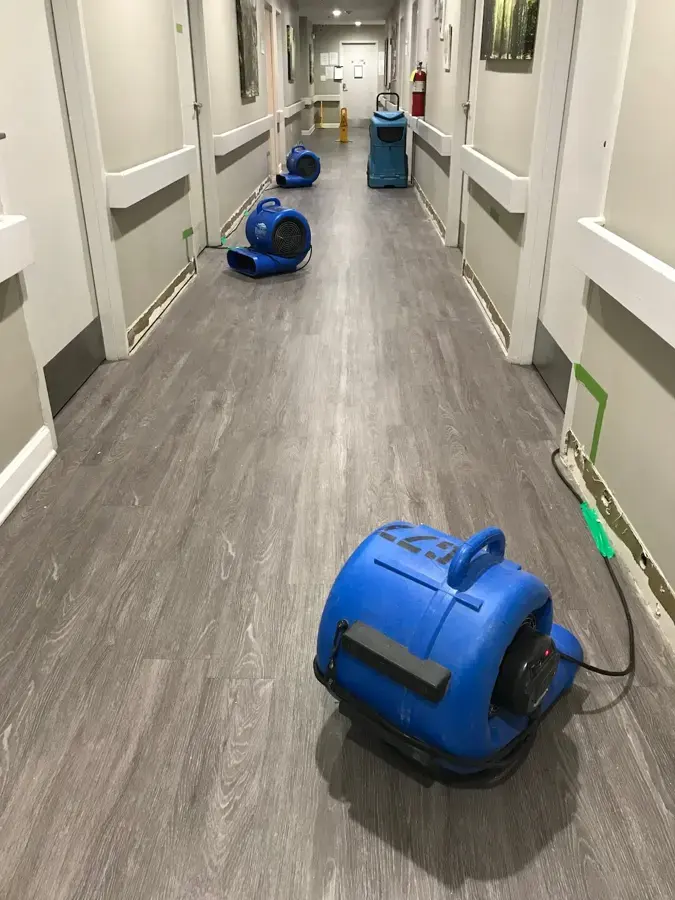 Air movers drying the floor of a long commercial corridor