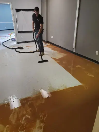 Technician running an extraction wand across a flooded floor to pull standing water in Lilburn
